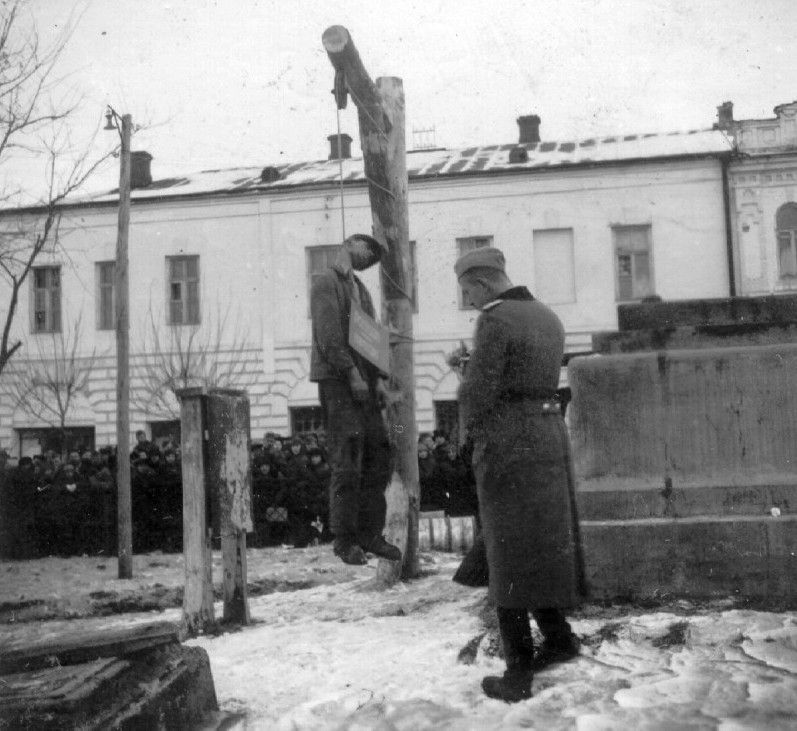 German soldier in Kiev stands next to an executed Soviet partisan